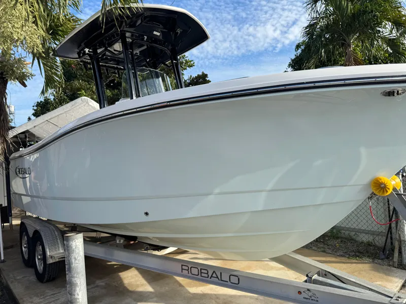 Slide: The Image of 2022 Robalo R230 Center Console boat on trailer, surrounded by palm trees. - 3
