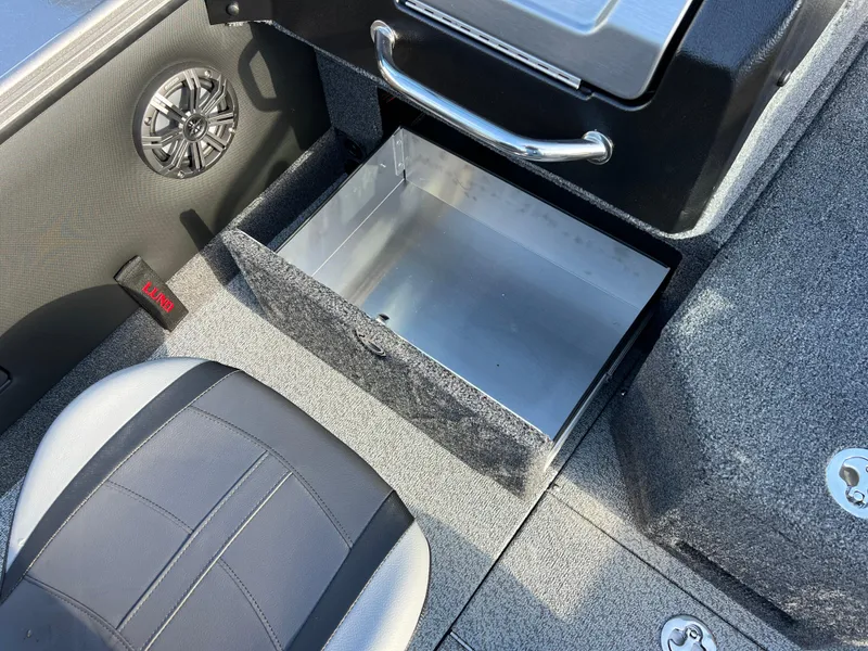 Slide: The Image of 2025 Lund 1875 Pro-V boat interior with open storage compartment and speaker. - 33