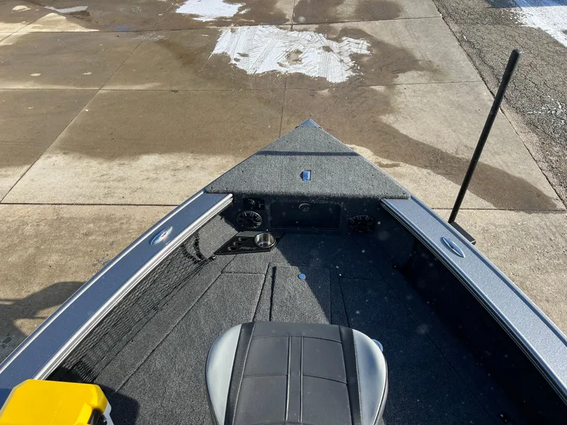 Slide: The Image of 2025 Lund 1875 Pro-V boat interior with seating and storage on a wet dock. - 9