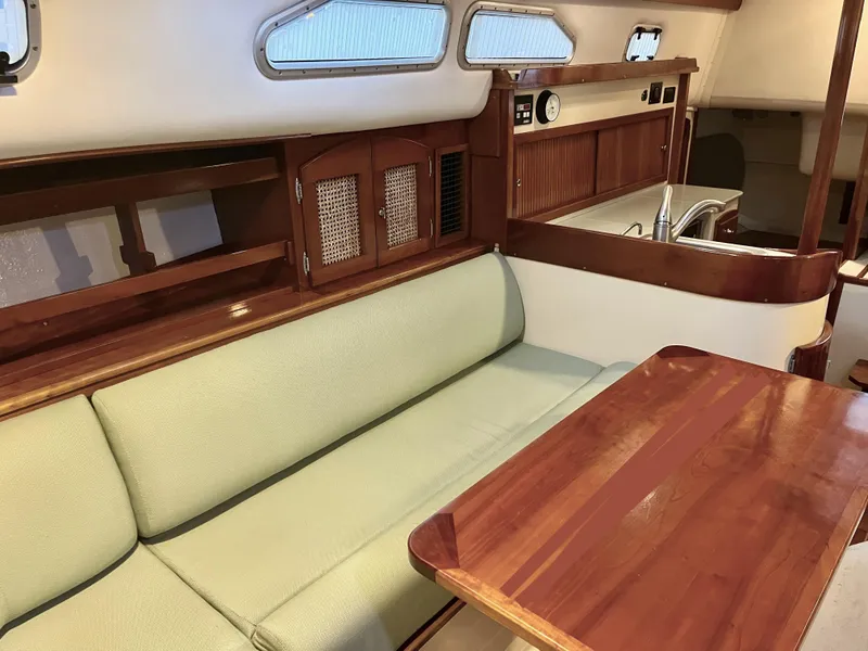 Slide: The Image of Interior of 2006 Shannon Shoalsailer with wooden table, green sofa, and compact kitchen area. - 12