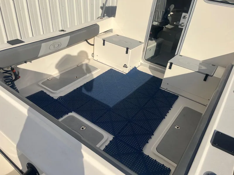 Slide: The Image of 2023 Defiance Admiral 220 EX boat interior with storage compartments and blue mat. - 11