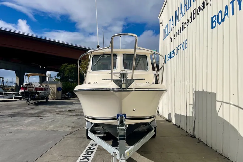 Slide: The Image of 2023 Defiance Admiral 220 EX boat on trailer at marina, under blue sky. - 2