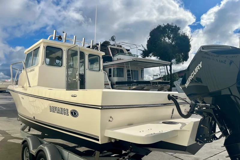 Slide: The Image of 2023 Defiance Admiral 220 EX boat with Mercury engine, docked under cloudy sky. - 5