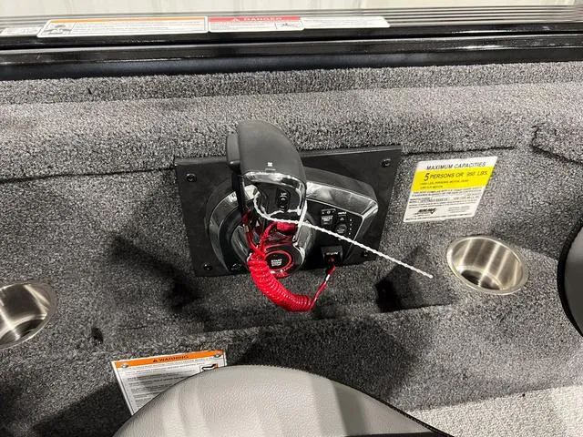 Slide: The Image of 2025 Lund 2075 Pro-V Bass XS boat control panel with safety features and cup holders. - 18