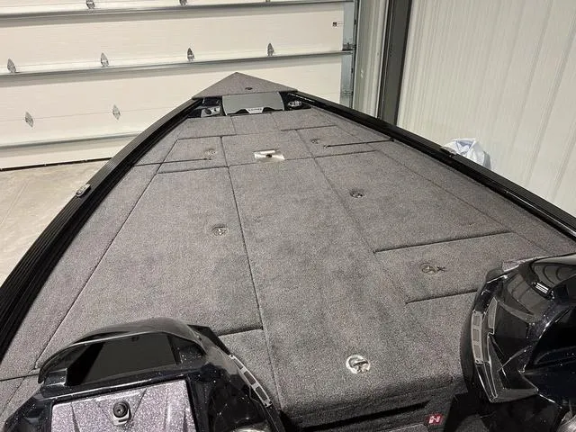 Slide: The Image of 2025 Lund 2075 Pro-V Bass XS boat interior with carpeted deck in a garage. - 23