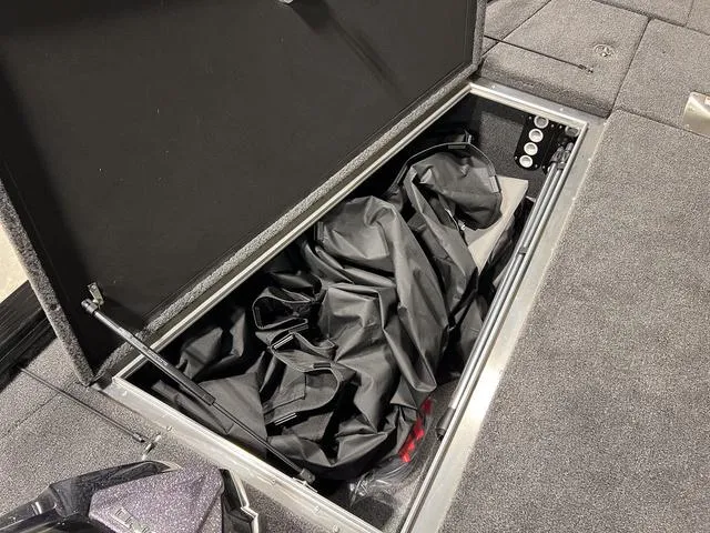 Slide: The Image of Storage compartment in 2025 Lund 2075 Pro-V Bass XS boat, featuring black fabric and organized space. - 25