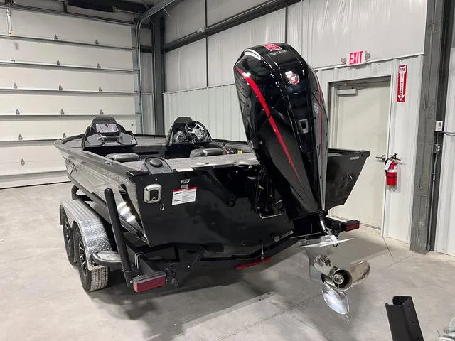 Slide: The Image of 2025 Lund 2075 Pro-V Bass XS boat in a garage, featuring a powerful outboard motor. - 4