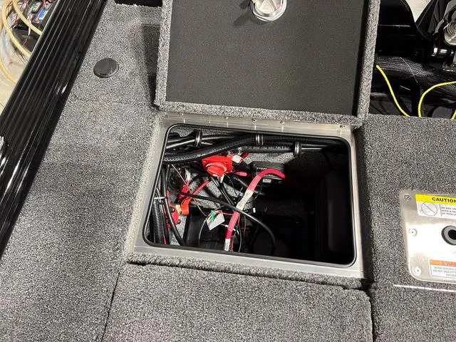 Slide: The Image of 2025 Lund 2075 Pro-V Bass XS battery compartment with wiring and storage access. - 8