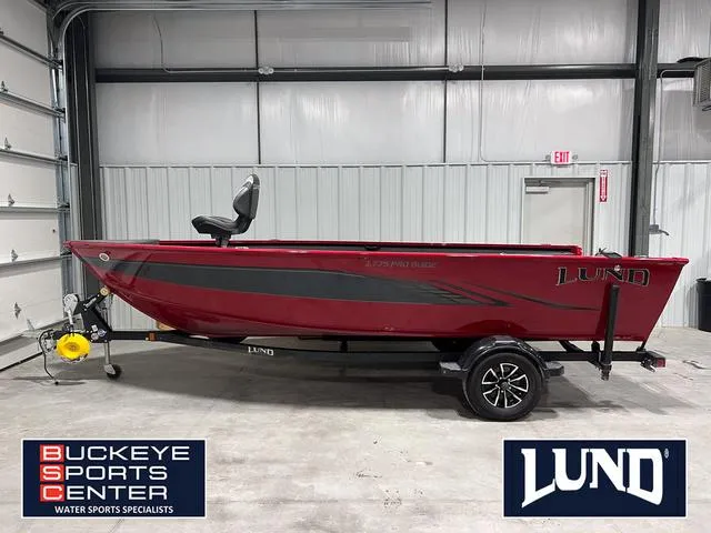 Slide: The Image of 2024 Lund 1775 Pro Guide Tiller boat cruising on a serene lake. - 1