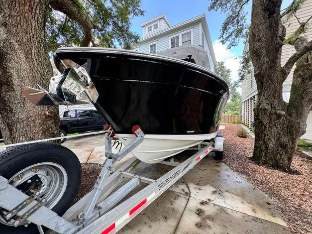 Slide: The Image of 2021 Blackfin 252 CC boat on trailer, parked near trees and houses. - 10