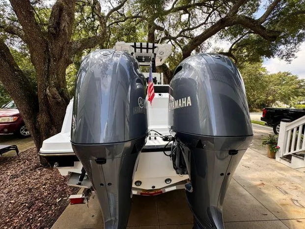Slide: The Image of 2021 Blackfin 252 CC boat with dual Yamaha outboard engines, parked under trees. - 16