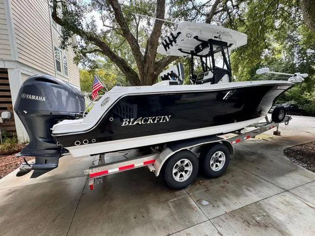 Slide: The Image of 2021 Blackfin 252 CC boat on trailer, parked outdoors, with Yamaha engine. - 2
