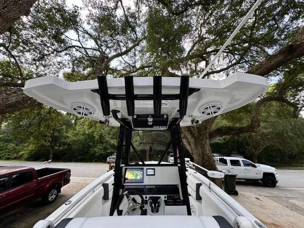 Slide: The Image of 2021 Blackfin 252 CC boat interior with T-top and electronics, parked under trees. - 24