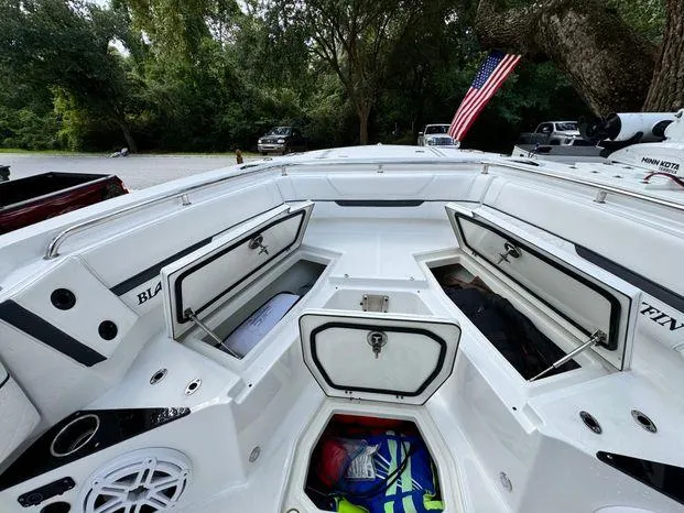 Slide: The Image of 2021 Blackfin 252 CC boat with open storage compartments and American flag in background. - 30