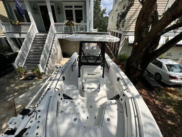 Slide: The Image of 2021 Blackfin 252 CC boat parked in residential driveway, surrounded by trees and houses. - 36