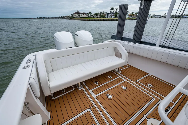 Slide: The Image of 2014 Intrepid 327 Center Console boat with teak deck and white seating, docked by the water. - 14