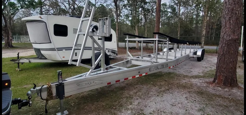 Slide: The Image of MTI 390X 2022 boat trailer parked near RV in wooded area. - 21