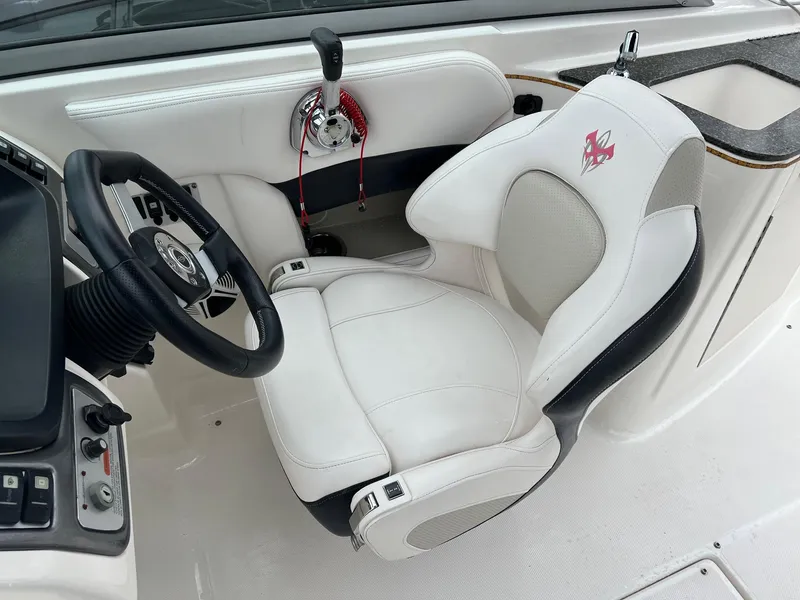 Slide: The Image of 2011 Chaparral Sunesta 244 Xtreme boat cockpit with white captain's chair and steering wheel. - 11