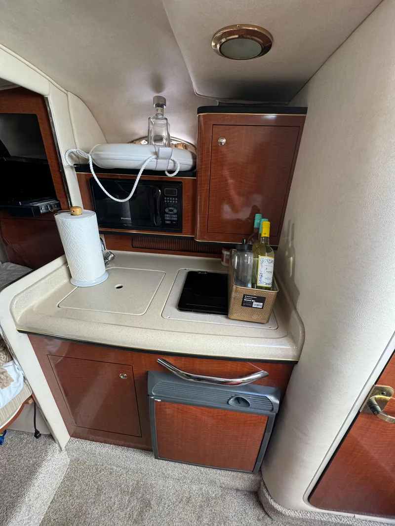 Slide: The Image of 2002 Sea Ray Sundancer cabin kitchen with microwave, sink, and storage cabinets. - 12