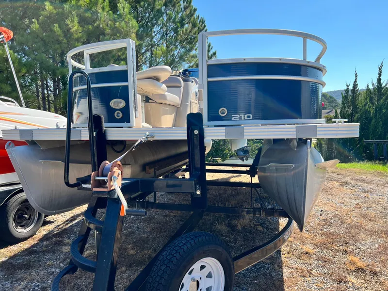 Slide: The Image of 2014 Crest 210FC pontoon boat on trailer, parked outdoors with trees in background. - 9