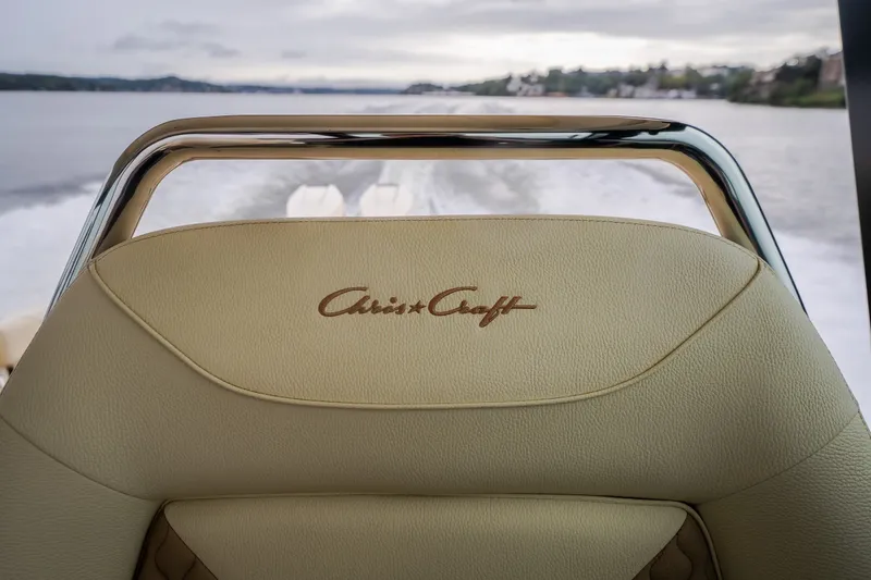Slide: The Image of 2024 Chris-Craft Calypso 32 boat seat with logo, cruising on a serene waterway. - 61