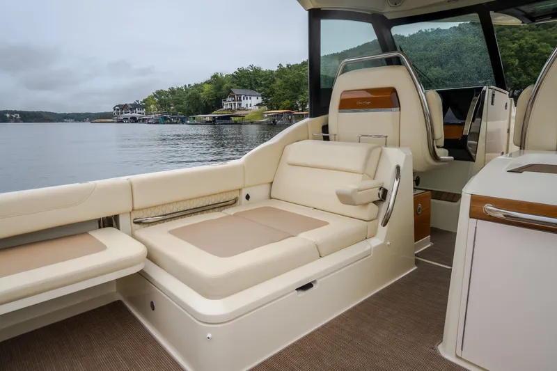 Slide: The Image of 2024 Chris-Craft Calypso 32 interior with luxurious seating, overlooking serene waterfront homes. - 23