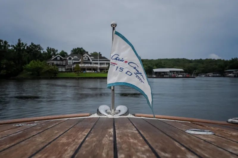 Slide: The Image of 2024 Chris-Craft Calypso 32 boat with flag, docked near waterfront homes. - 55