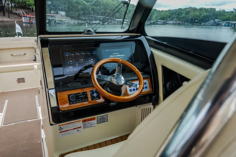Slide: The Image of 2024 Chris-Craft Calypso 32 helm with wooden steering wheel and modern dashboard display. - 33