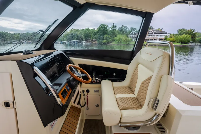 Slide: The Image of 2024 Chris-Craft Calypso 32 helm with luxurious seating and advanced controls on a serene lake. - 32