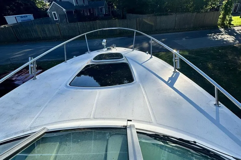 Slide: The Image of 2013 Sea Ray 280 Sundancer boat deck with railing and hatch, parked near a residential area. - 13