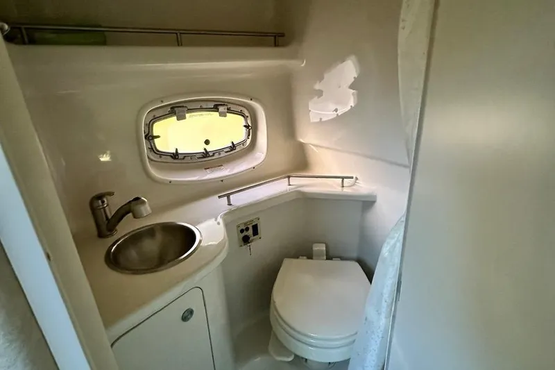 Slide: The Image of 2013 Sea Ray 280 Sundancer bathroom with sink, toilet, and porthole window. - 17