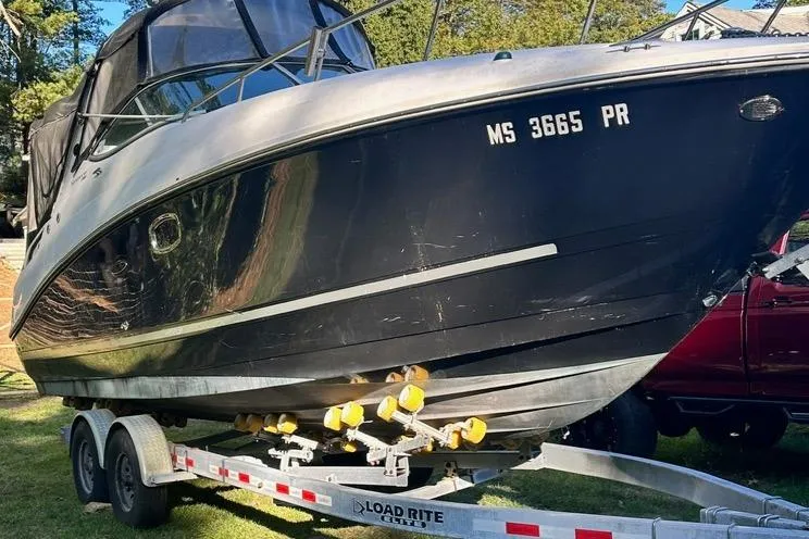 Slide: The Image of 2013 Sea Ray 280 Sundancer boat on trailer, black hull, parked on grass. - 6