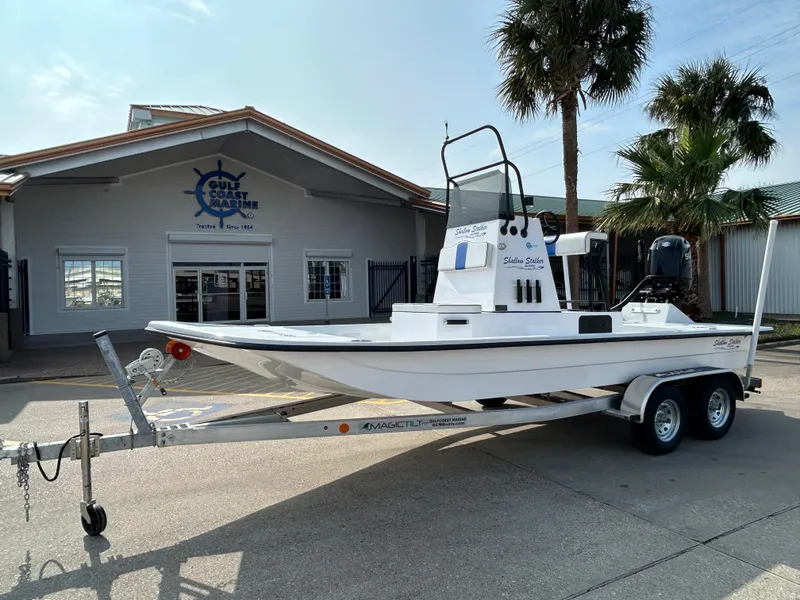The Image of 2025 Shallow Stalker Cat 204 boat on trailer outside dealership, palm trees in background. - 0