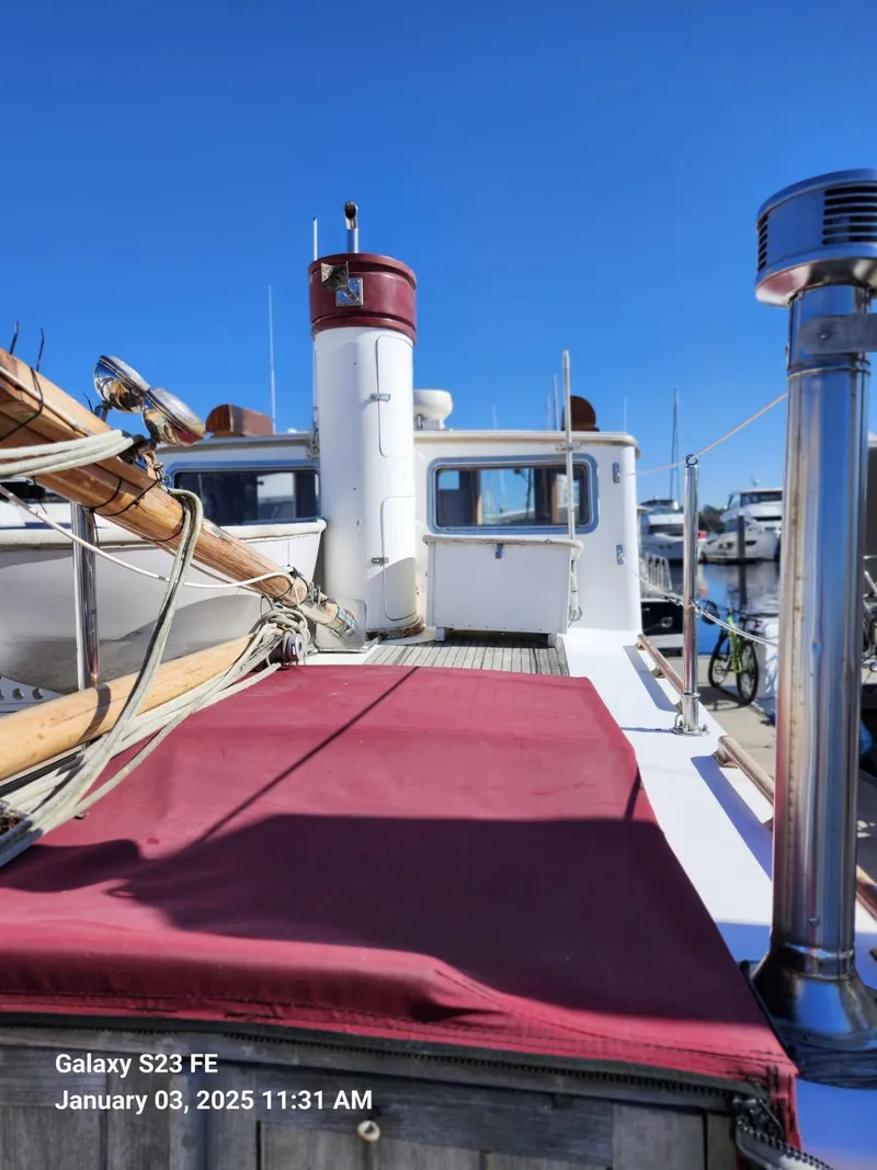 Slide: The Image of 1988 Lord Nelson Victory 37 boat deck with red cover, docked under clear blue sky. - 17
