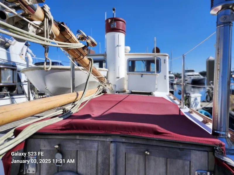 Slide: The Image of Lord Nelson Victory 37 sailboat deck with red cover, docked in marina, clear blue sky. - 18