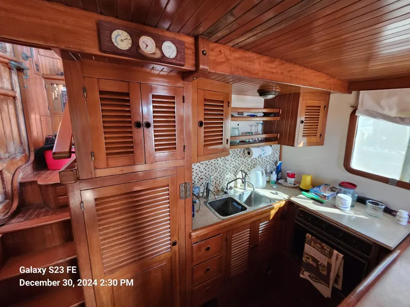 Slide: The Image of Wooden interior of 1988 Lord Nelson Victory 37 yacht kitchen with cabinets and sink. - 37