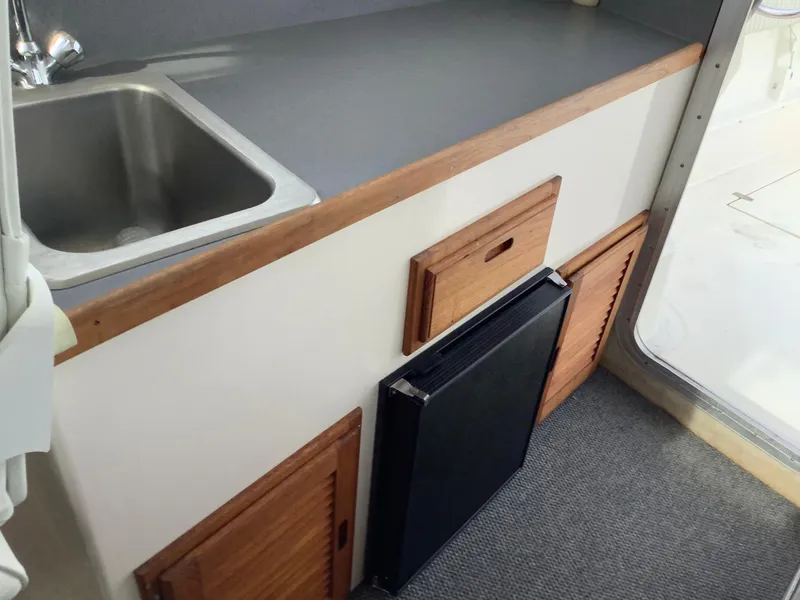 Slide: The Image of Compact kitchen area in 2018 Osprey 26 Long Cabin boat with sink and storage. - 12