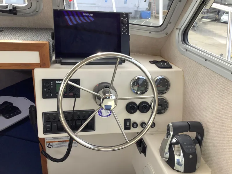 Slide: The Image of 2018 Osprey 26 Long Cabin boat helm with steering wheel, gauges, and navigation equipment. - 8