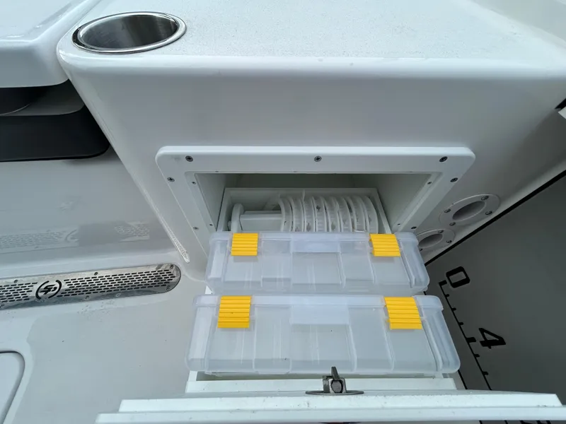 Slide: The Image of Storage compartment on 2024 Sea Pro 250 DLX boat with tackle boxes and cup holder. - 10