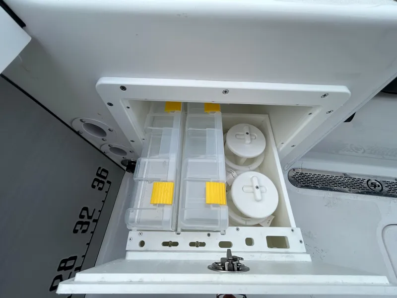 Slide: The Image of Storage compartment on a 2024 Sea Pro 250 DLX boat with organized containers. - 12
