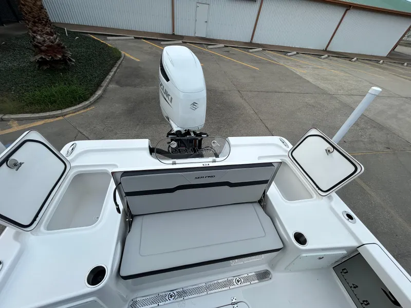 Slide: The Image of 2024 Sea Pro 250 DLX boat with open storage compartments and outboard motor. - 7