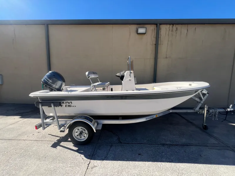 Slide: The Image of 2025 Carolina Skiff E 16 JVX boat on trailer, parked outdoors. - 1