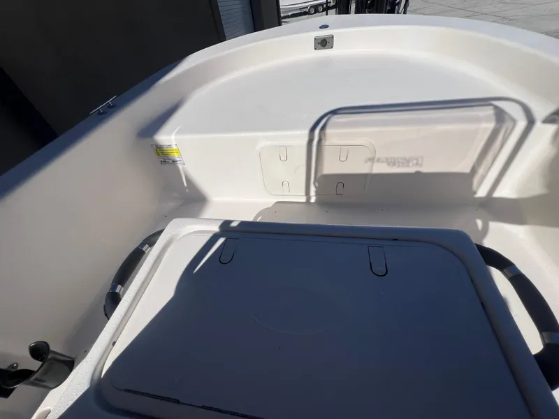 Slide: The Image of 2025 Carolina Skiff E 16 JVX boat interior, featuring storage compartment and seating area. - 16