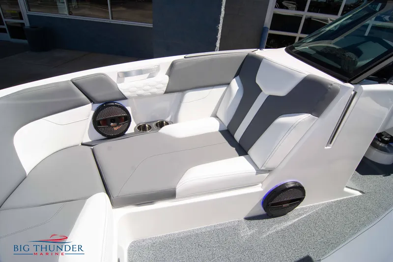 Slide: The Image of 2024 MasterCraft NXT24 boat interior with gray and white seating, cup holders, and speakers. - 48