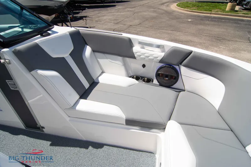 Slide: The Image of 2024 MasterCraft NXT24 boat interior with gray and white seating, cup holders, and speaker. - 49
