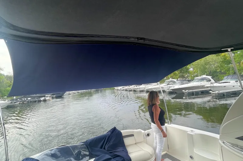 Slide: The Image of 2003 Sea Ray 420 Sundancer yacht with a woman standing under a canopy, docked at a marina. - 10