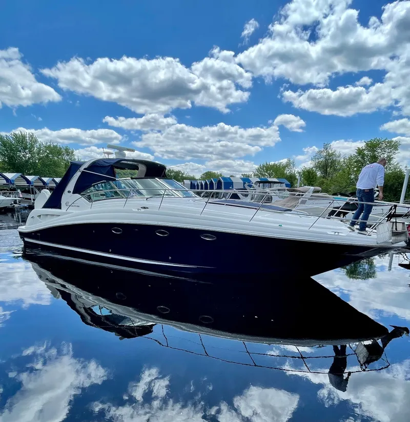 Slide: The Image of 2003 Sea Ray 420 Sundancer yacht on calm water under a blue sky with clouds. - 2