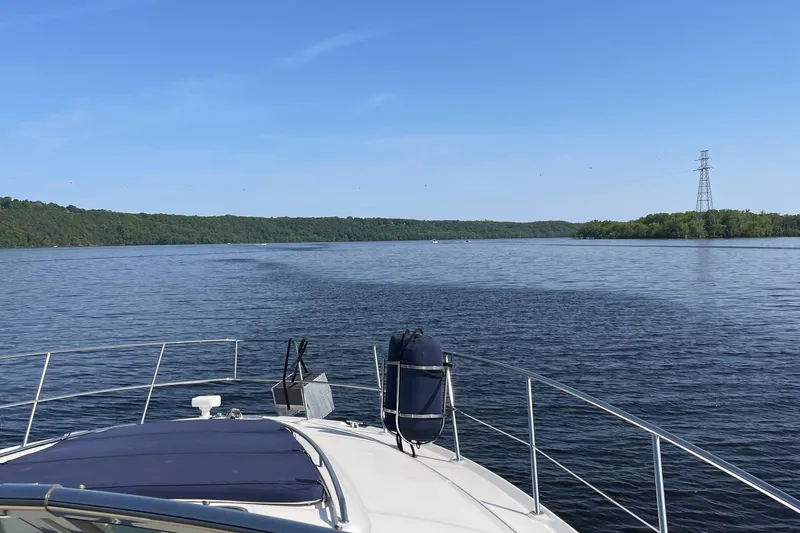 Slide: The Image of 2003 Sea Ray 420 Sundancer cruising on a serene lake under a clear blue sky. - 6