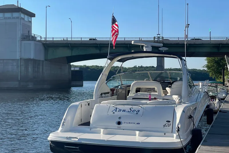 Slide: The Image of 2003 Sea Ray 420 Sundancer docked near a bridge, displaying an American flag. - 8