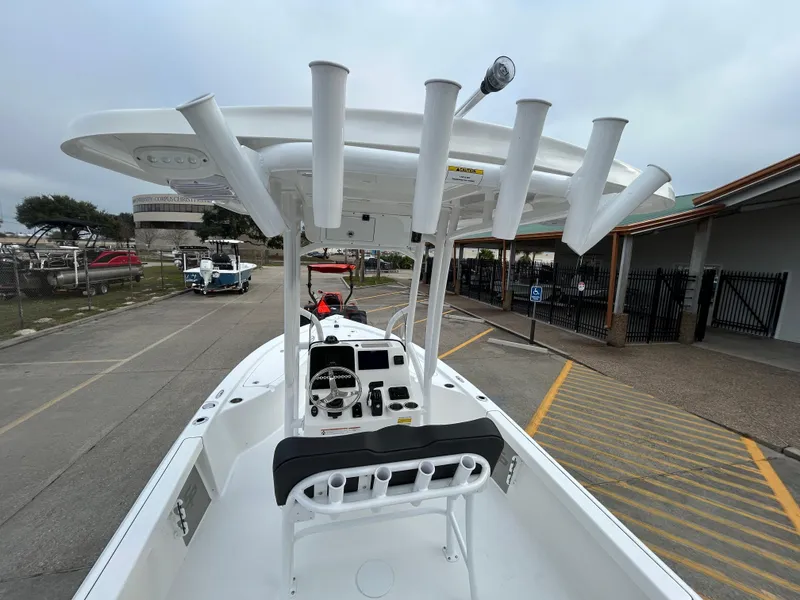 Slide: The Image of 2025 Sea Pro 210 Bay boat with T-top and rod holders in a parking area. - 14